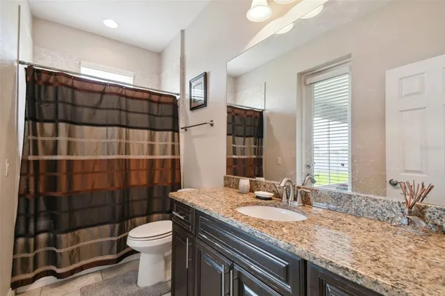 a bathroom with a granite countertop sink a toilet a mirror and shower