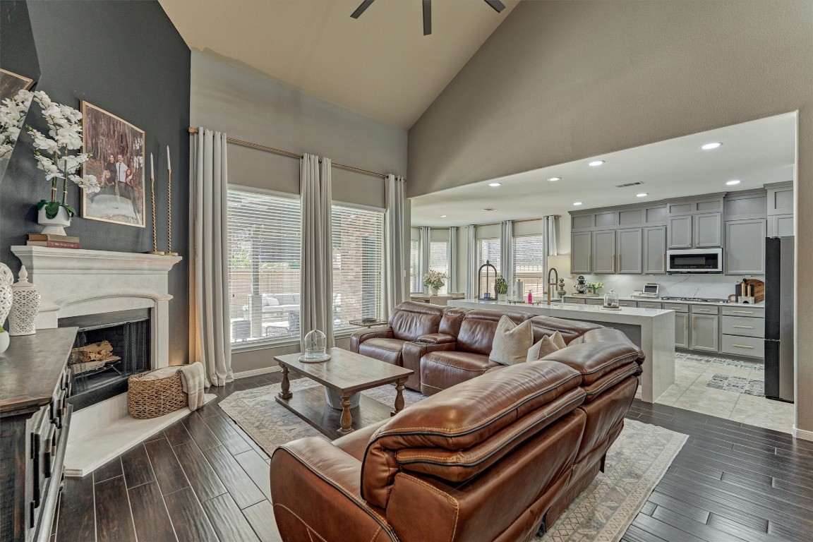 226 Hampton Glen Road Montgomery, TX 77356 - Photo 12 of 48 This photo showcases a spacious open-concept living area with high ceilings, featuring a cozy fireplace and elegant wood-like tile flooring. Large windows allow plenty of natural light.