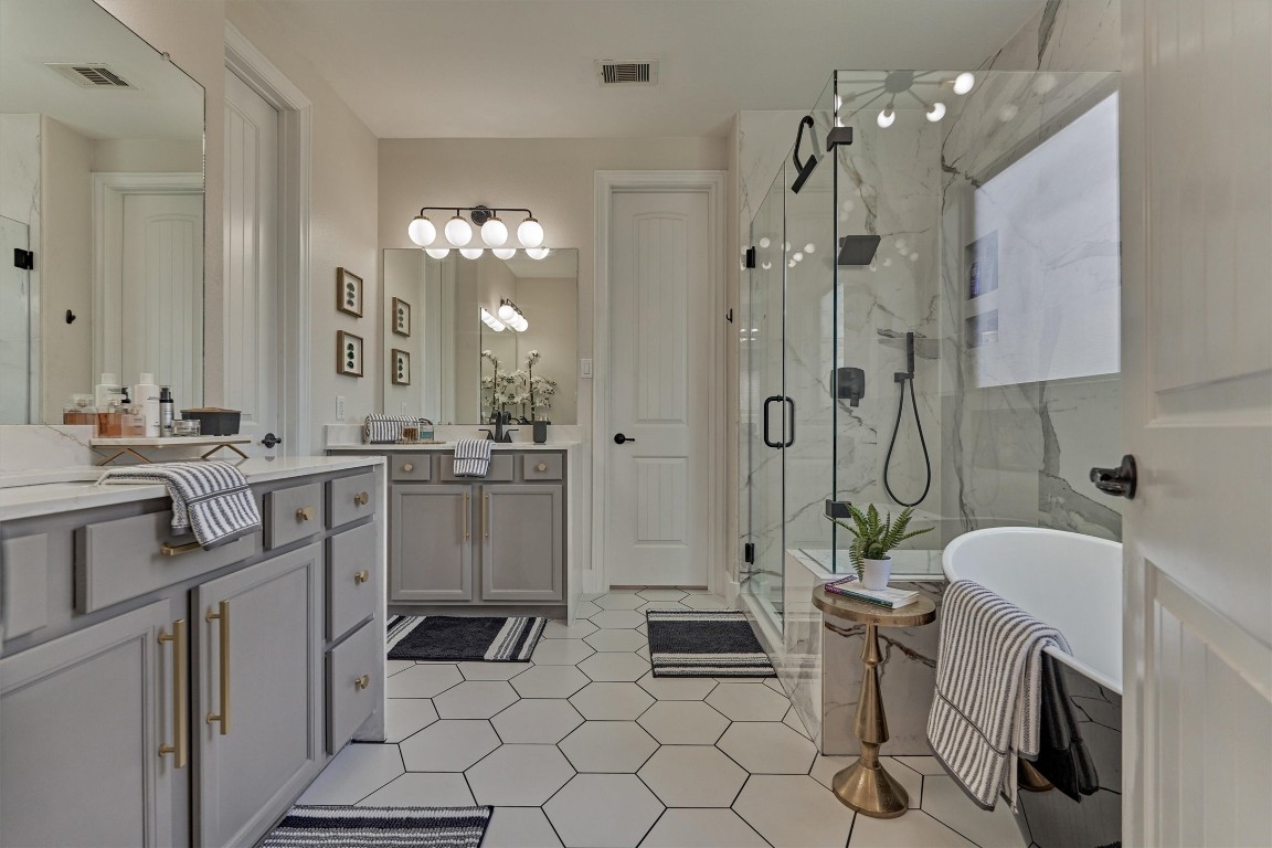 226 Hampton Glen Road Montgomery, TX 77356 - Photo 20 of 48 This recently updated bathroom features a modern design with hexagonal tile flooring, a spacious glass-enclosed shower, a freestanding bathtub, and dual sink vanities with elegant fixtures. The neutral color palette and ample lighting create a bright and inviting space.