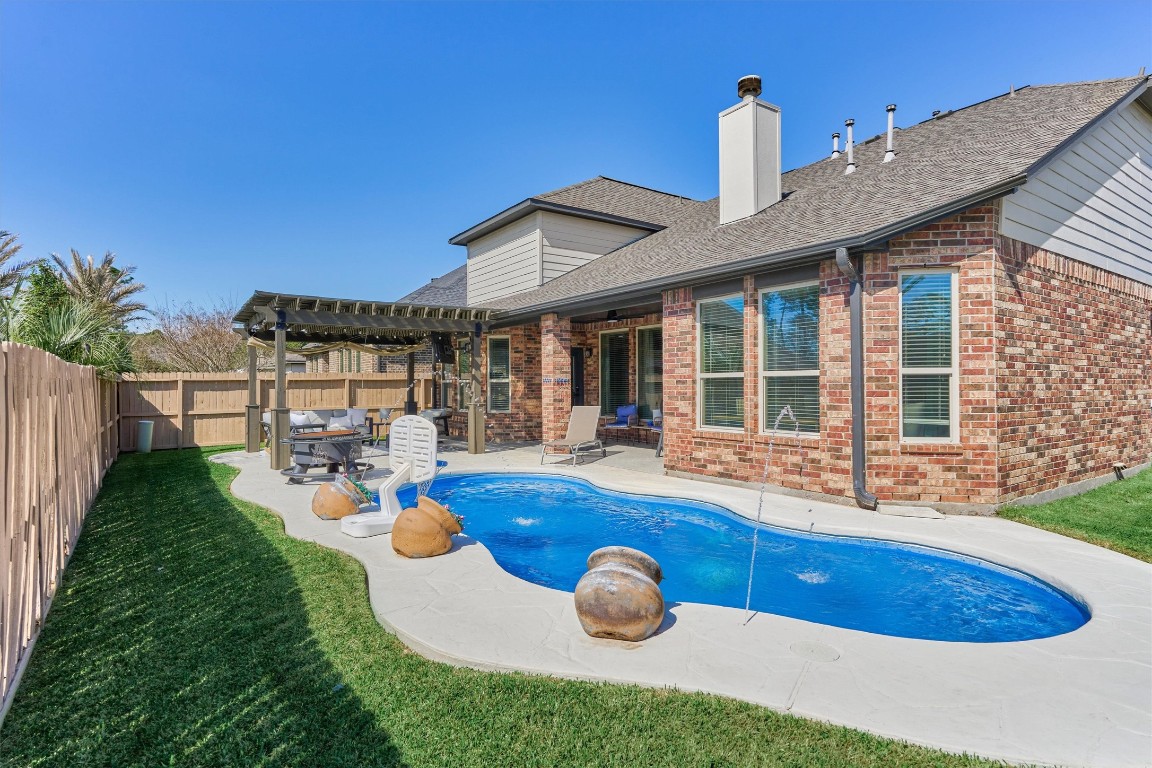 226 Hampton Glen Road Montgomery, TX 77356 - Photo 36 of 48 This backyard features a pool with a surrounding patio area and a covered pergola with outdoor seating. The brick house has large windows and a fenced perimeter, offering privacy and relaxation.