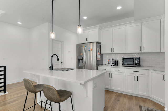 8307 Durham Street Sandy, UT 84070 - Photo 8 of 29 Modern kitchen featuring white shaker cabinetry, stainless steel refrigerator, white subway tile backsplash, and light wood-finish flooring