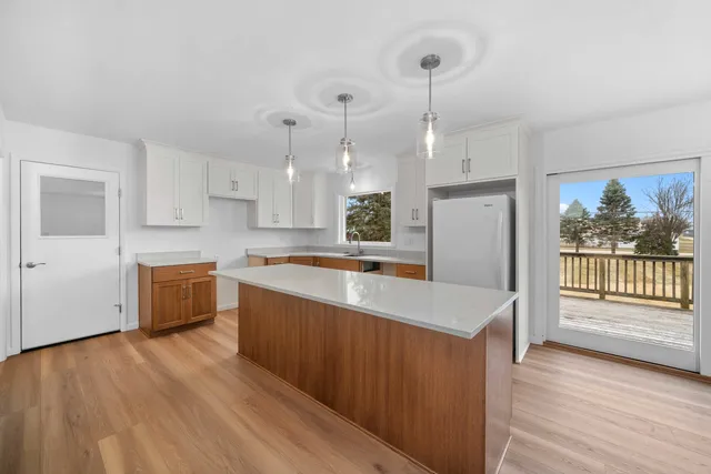 a large kitchen with stainless steel appliances granite countertop a refrigerator a sink dishwasher a stove and white countertops with wooden floor
