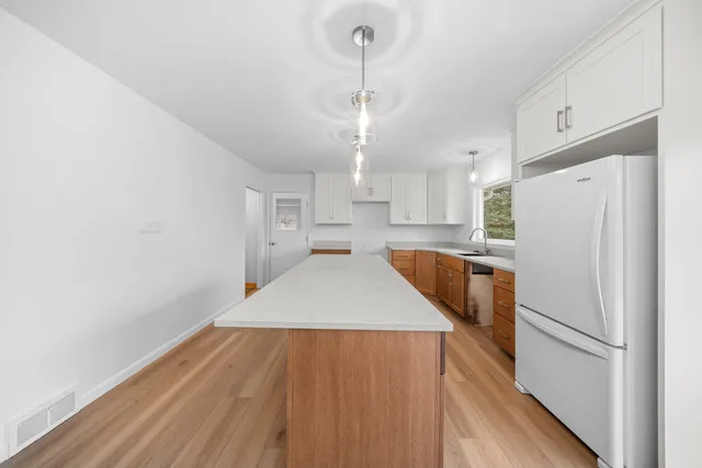 a kitchen with wooden floor sink and refrigerator