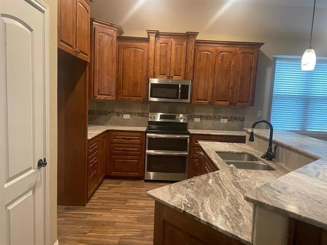 a kitchen with kitchen island granite countertop a stove microwave and refrigerator
