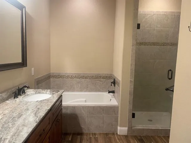 a bathroom with a granite countertop sink and mirror with bathtub