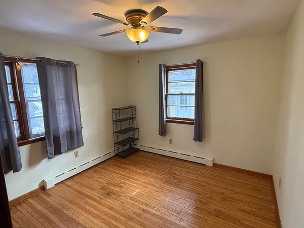 a view of an empty room with a window and wooden floor