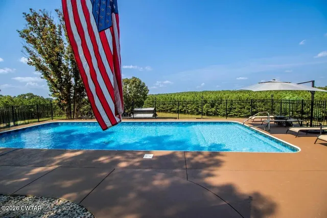 a view of a backyard with swimming pool and trees