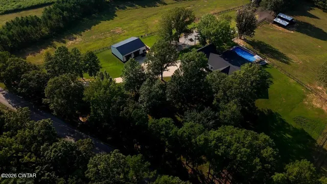an aerial view of residential house with outdoor space and trees all around
