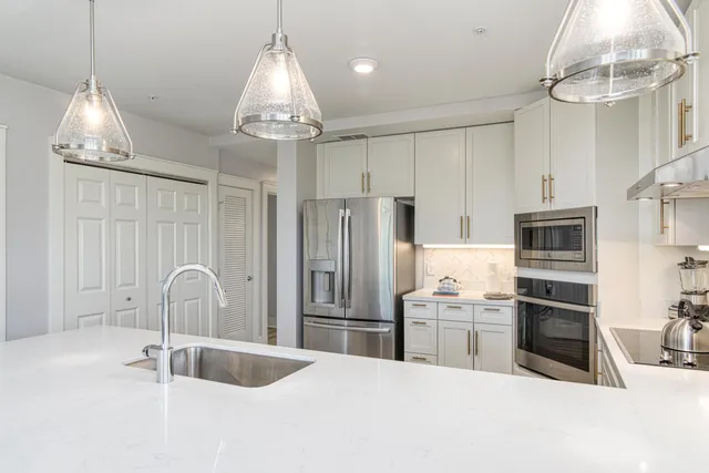 a kitchen with stainless steel appliances granite countertop a sink refrigerator and cabinets