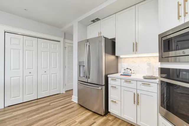 a kitchen with cabinets stainless steel appliances and wooden floor