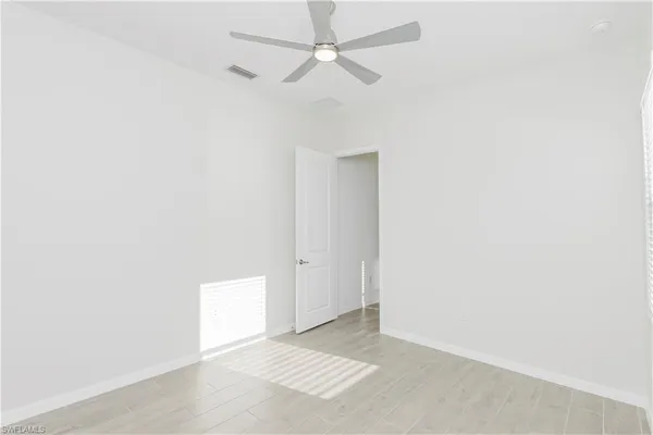 an empty room with a ceiling fan and a window
