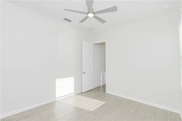 an empty room with a ceiling fan and a window