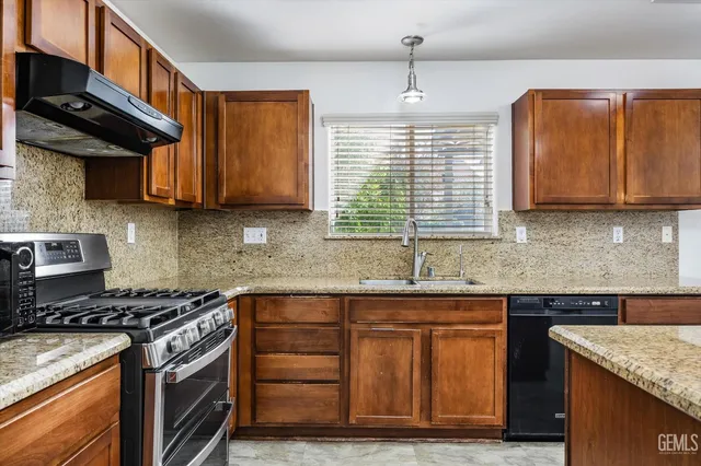 a kitchen with granite countertop a stove sink and cabinets