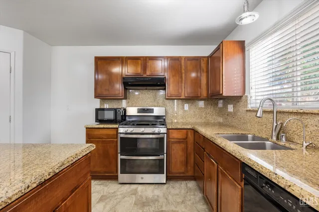 a kitchen with stainless steel appliances granite countertop a sink stove and oven