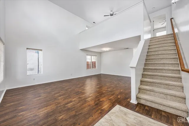 a view of an empty room with wooden floor and stairs