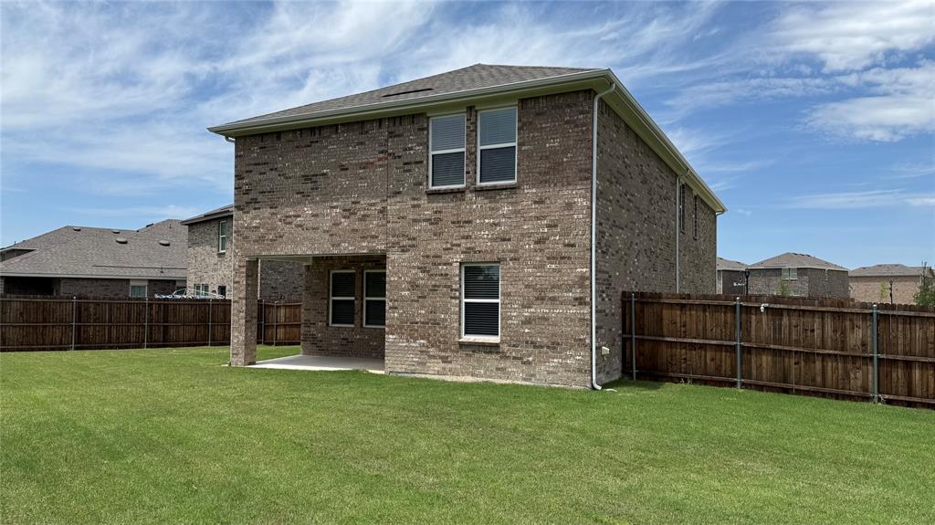 4529 Winecup Road Melissa, TX 75454 - Photo 26 of 29 Expansive green lawn surrounds the brick exterior of this residence, featuring a covered patio with a concrete slab