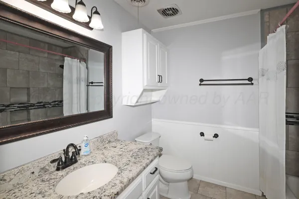 a bathroom with a granite countertop sink a toilet and a mirror