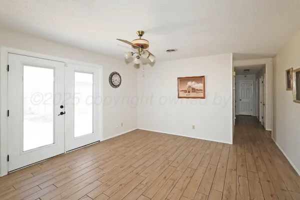 a view of a big room with wooden floor and windows