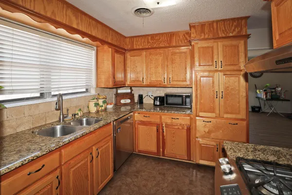 a kitchen with stainless steel appliances granite countertop a sink a stove and a refrigerator