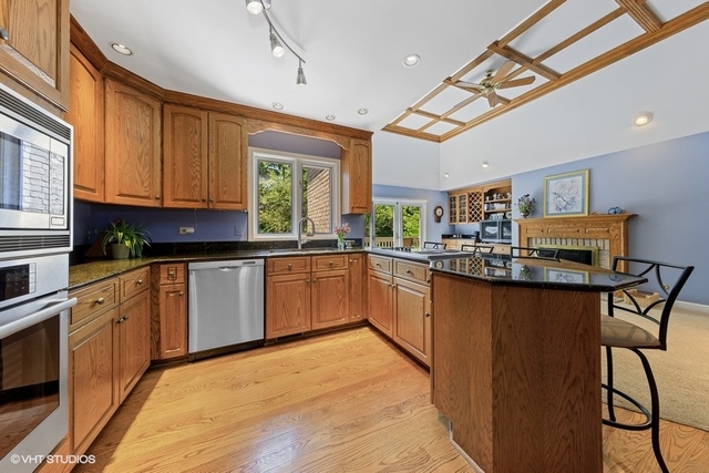 16 Tartan Ridge Road Burr Ridge, IL 60527 - Photo 6 of 30 a kitchen with stainless steel appliances kitchen island granite countertop a stove a sink dishwasher and white cabinets with wooden floor
