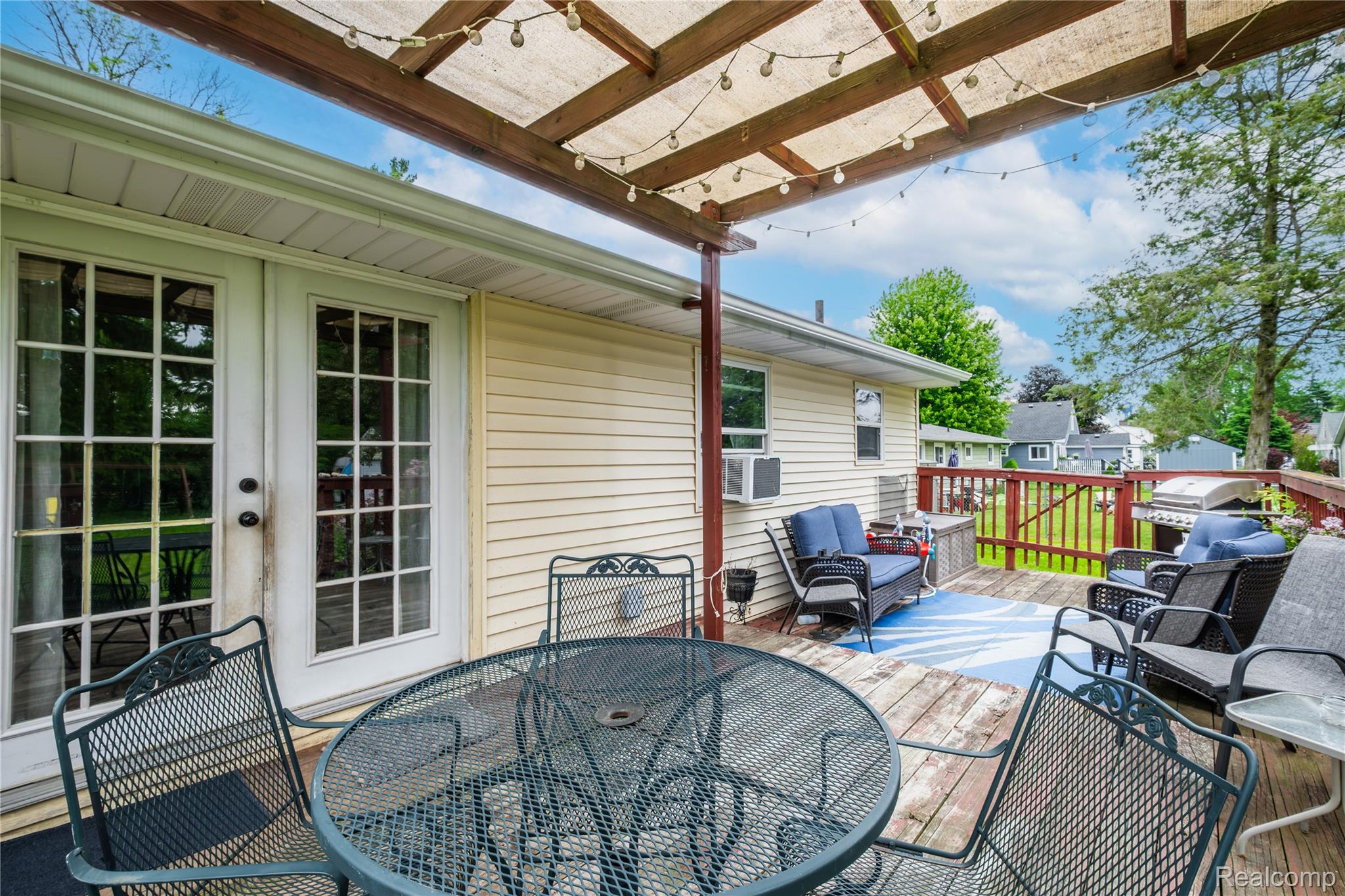 7800 Maple Street Birch Run, MI 48415 - Photo 23 of 29 Expansive multi-level wood-finish deck featuring a partial overhead covering with string lighting, a railing system, and dual glass-paned doors providing direct outdoor access