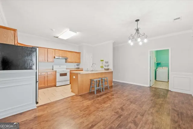 a view of a kitchen with kitchen island a counter top space a sink stainless steel appliances and cabinets
