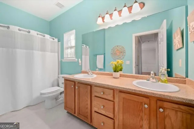a bathroom with a granite countertop sink a toilet a mirror and shower curtain