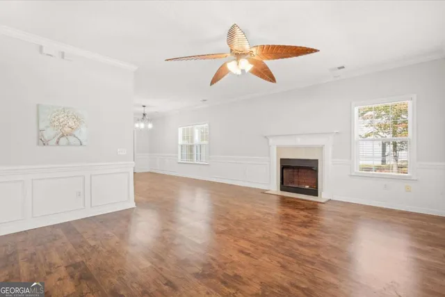a view of an empty room with window and wooden floor