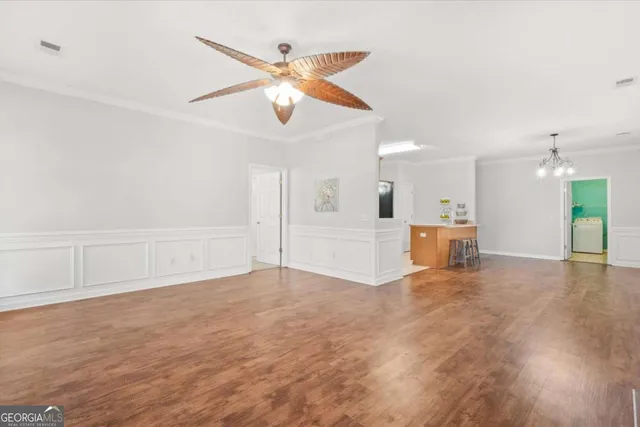 an empty room with wooden floor ceiling fan and windows