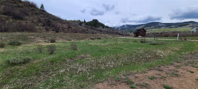 a view of a lush green outdoor space with a swimming pool and valleys in the background