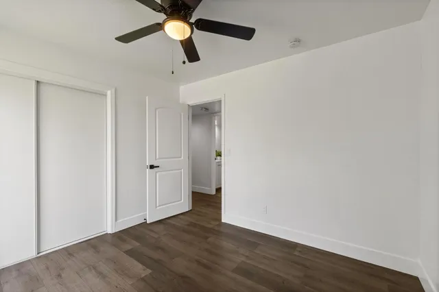 an empty room with wooden floor a ceiling fan and closet