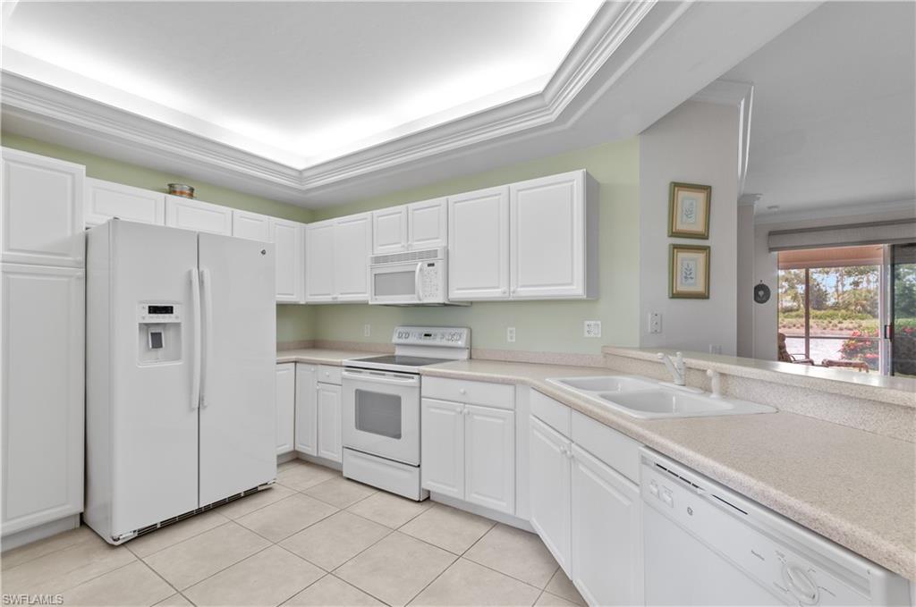 9341 Spring Run Boulevard, Unit 3106 Estero, FL 34135 - Photo 5 of 44 Kitchen featuring white appliances, white cabinets, light countertops, and crown molding