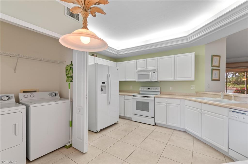 9341 Spring Run Boulevard, Unit 3106 Estero, FL 34135 - Photo 8 of 44 Kitchen with white appliances, white cabinets, light tile floors, light countertops, and washing machine and dryer