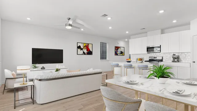 a room with stainless steel appliances kitchen island granite countertop a sink a stove a microwave a dining table and chairs