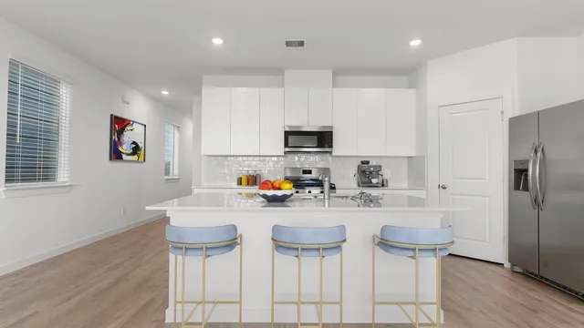 a kitchen with stainless steel appliances a dining table chairs refrigerator and sink