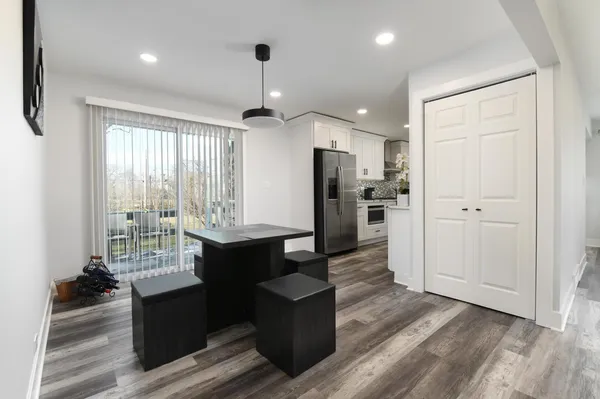 a kitchen with stainless steel appliances kitchen island granite countertop a refrigerator and a wooden floor