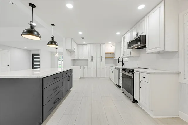 a kitchen with stainless steel appliances granite countertop a sink a stove and a refrigerator