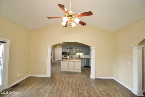 a view of an empty room with wooden floor and a ceiling fan