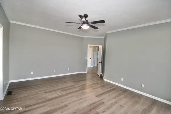 an empty room with wooden floor and a ceiling fan