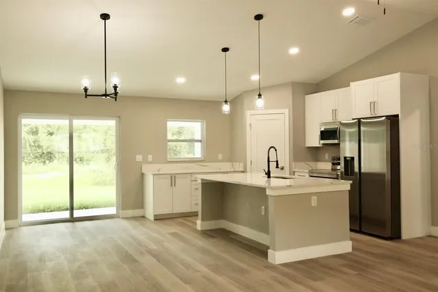 a kitchen with kitchen island a counter top space appliances and a large window