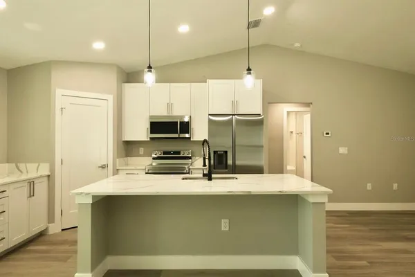 a kitchen with kitchen island a sink stainless steel appliances and cabinets