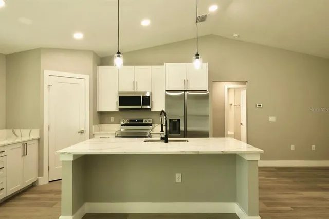 a kitchen with kitchen island a sink stainless steel appliances and cabinets