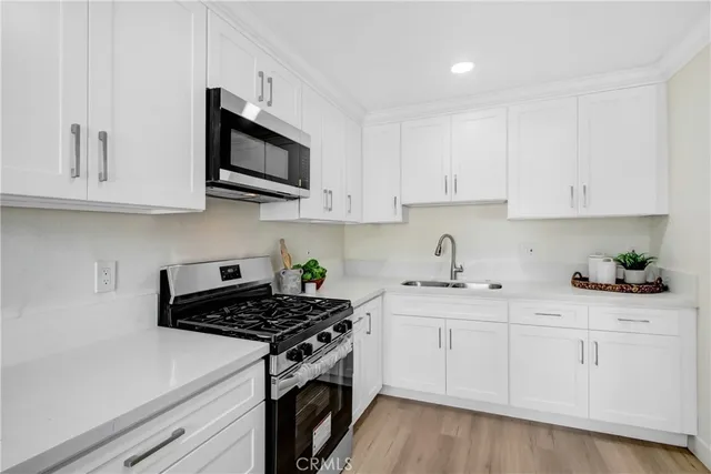a kitchen with stainless steel appliances granite countertop white cabinets a stove a sink and dishwasher