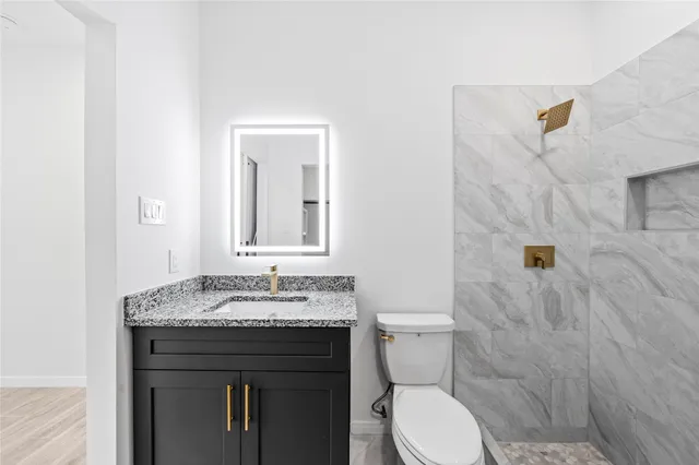 a bathroom with a granite countertop sink toilet and shower
