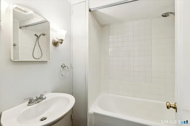 a white bath tub sitting next to a white sink and a shower