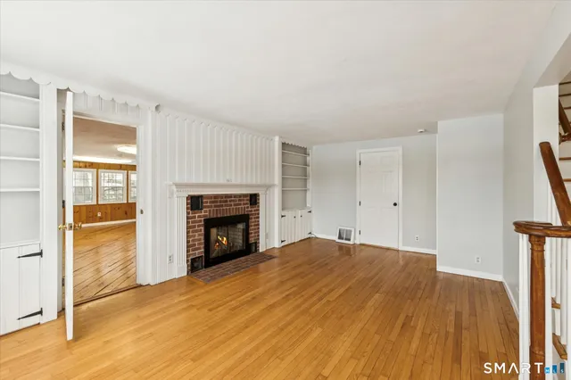 a view of empty room with fireplace and wooden floor