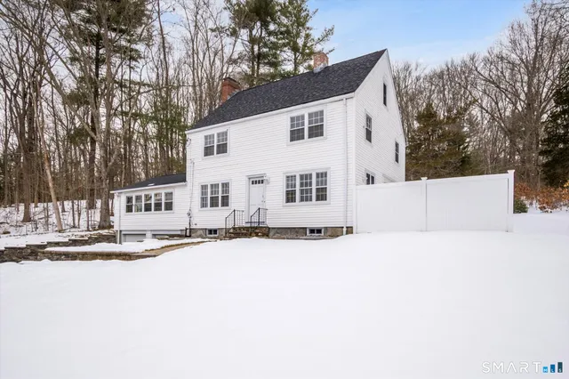 a view of a white house with a yard covered with snow in the back