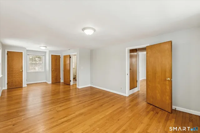 a view of an empty room with window and wooden floor