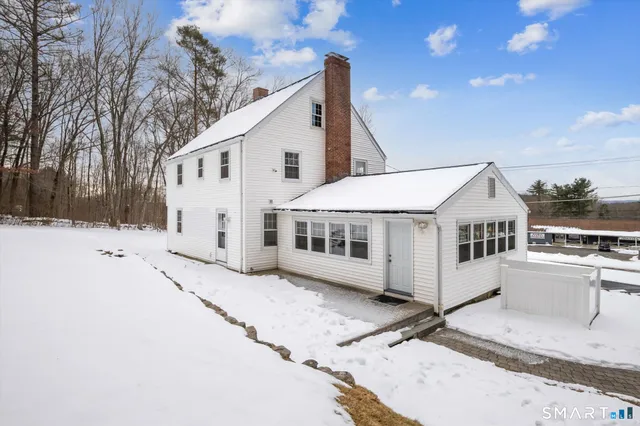 a view of a white house with a yard covered in snow