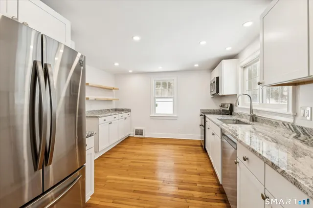 a large kitchen with stainless steel appliances granite countertop a refrigerator and a sink